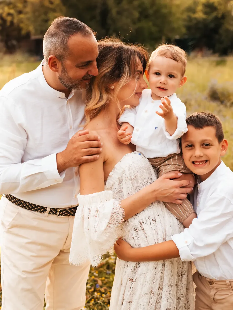 Famiglia con due bambini abbracciati in un prato al tramonto, servizio fotografico Milano