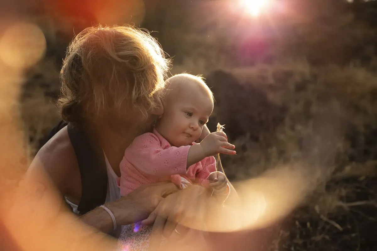 Mamma che coccola neonata in rosa nella luce calda del tramonto