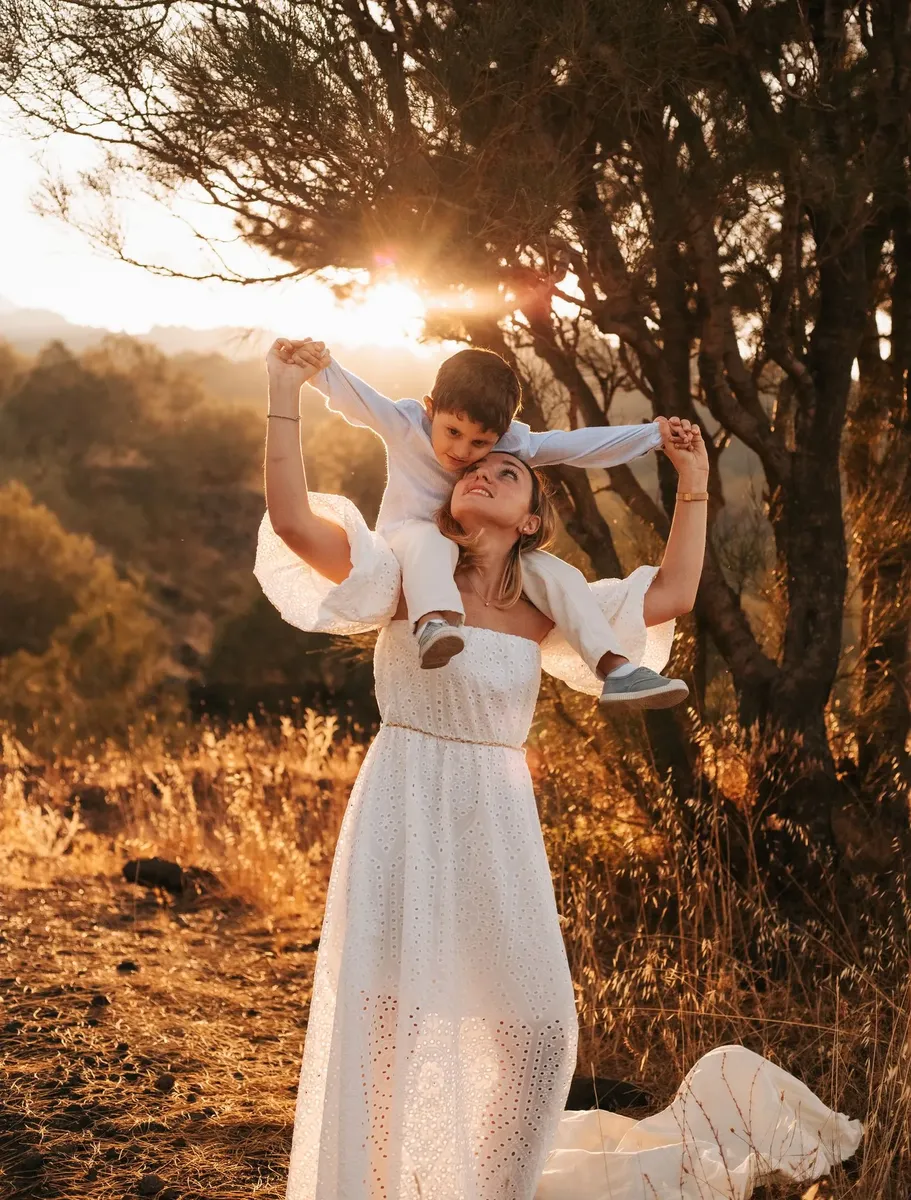 Mamma che porta il figlio sulle spalle al tramonto, servizio famiglia all'aperto