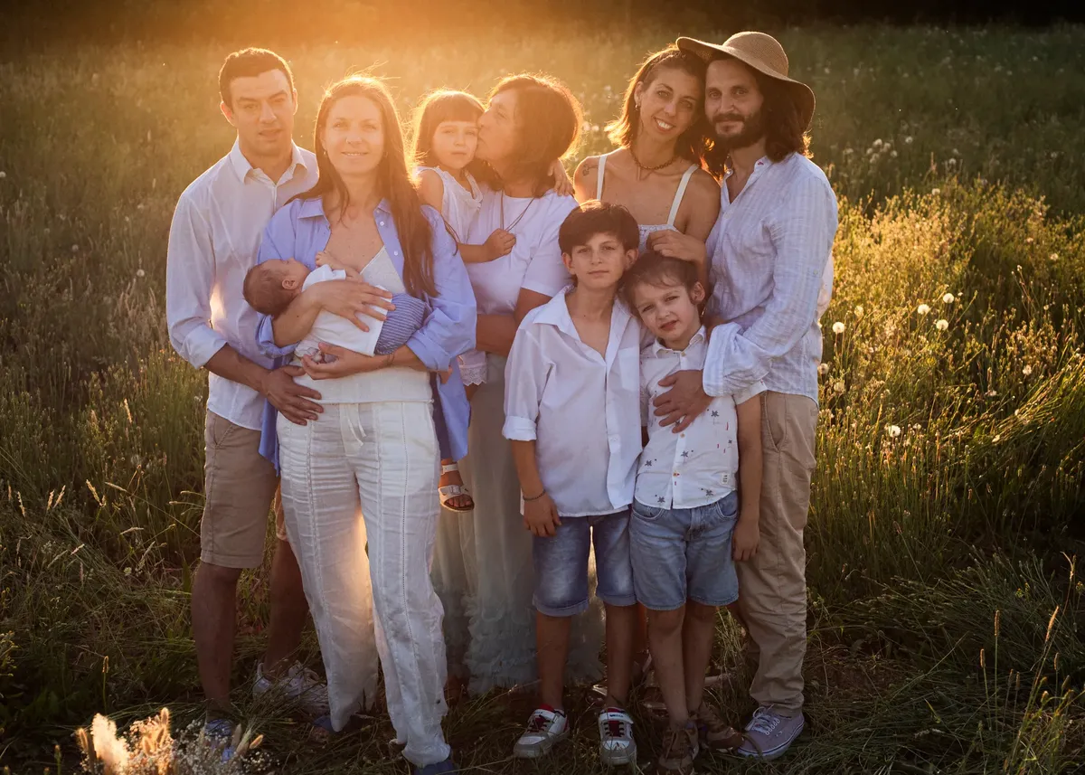 Due famiglie con bambini e neonato riunite in un prato al tramonto