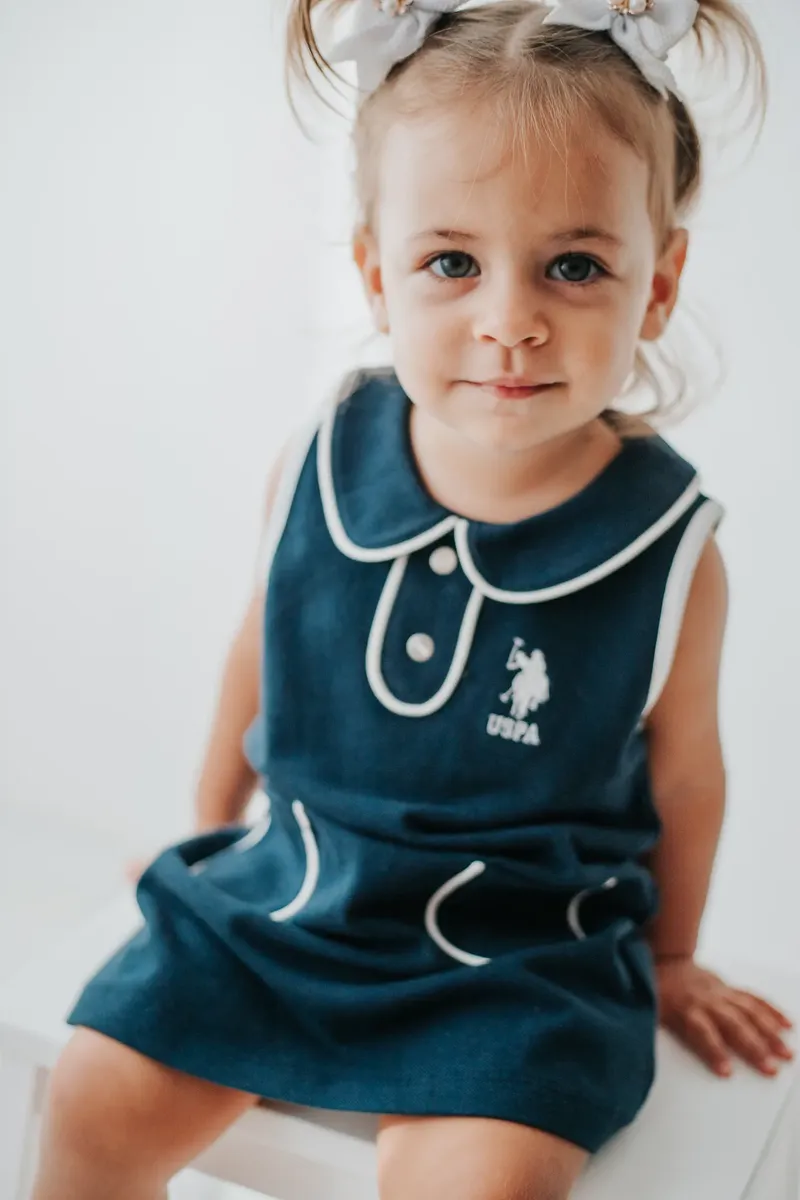 Ritratto di bimba con fiocchi nei capelli e vestito blu in studio fotografico Milano
