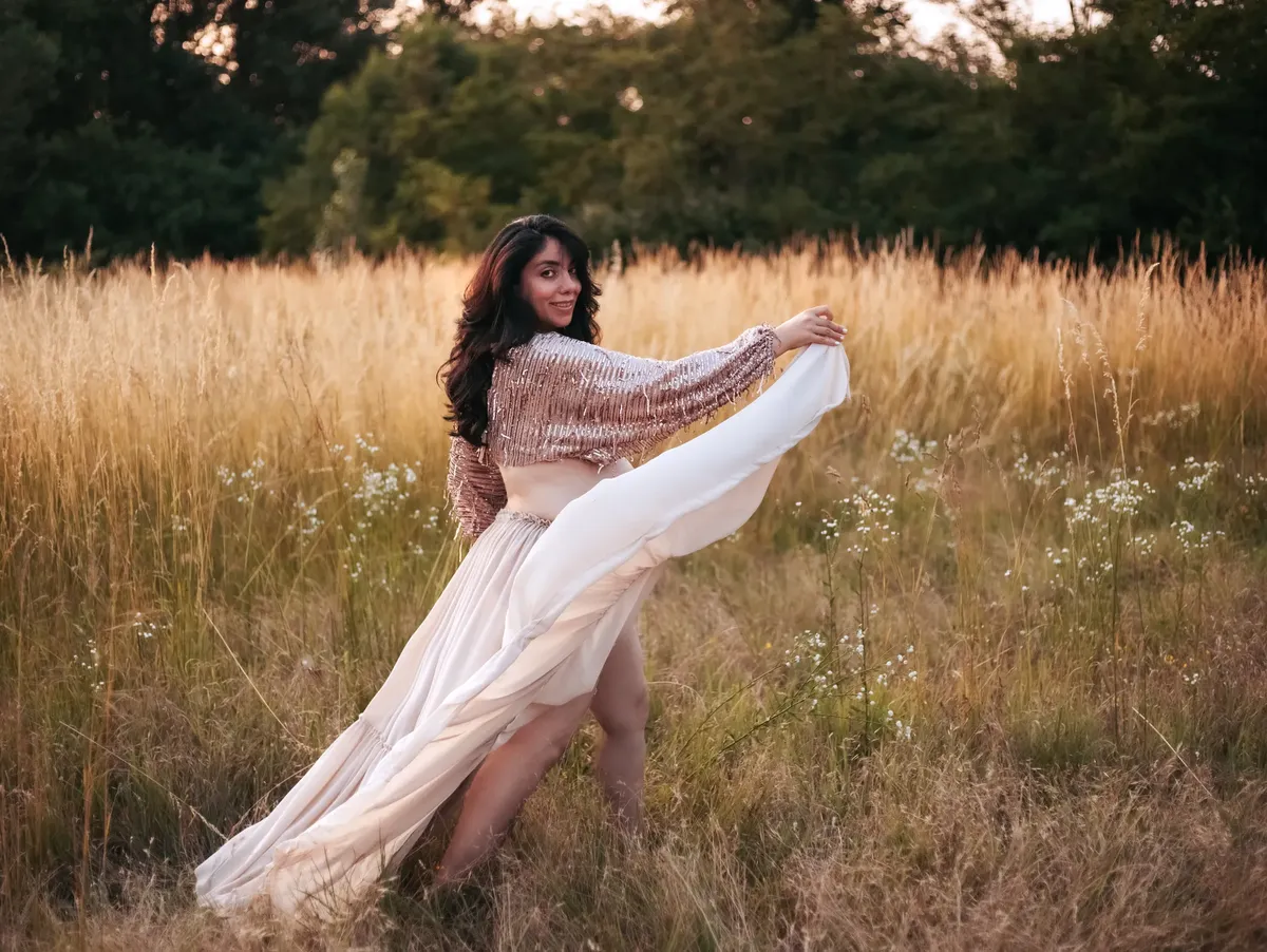 Donna incinta danza in un campo dorato al tramonto con abito elegante