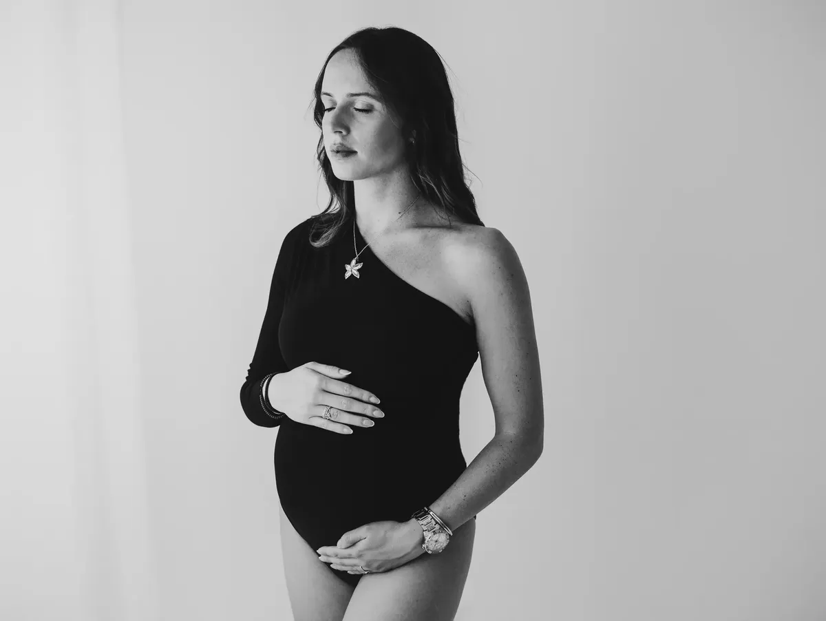 Ritratto in bianco e nero di donna incinta con body nero monospalla in studio