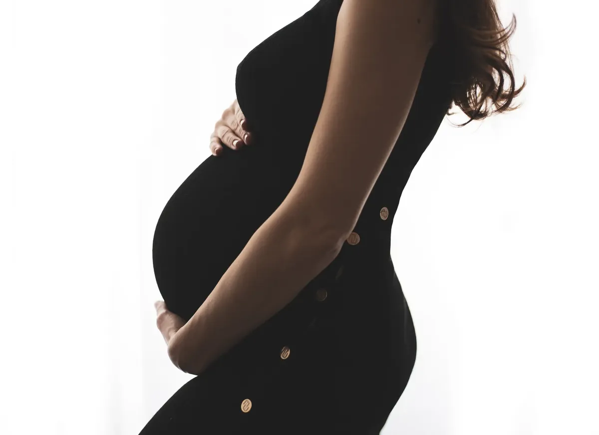 Silhouette profilo pancione in controluce con abito nero aderente, fotografo maternita Milano
