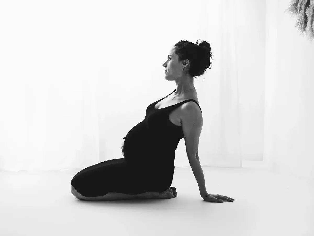 Donna incinta in body nero in posa di profilo in bianco e nero, servizio premaman