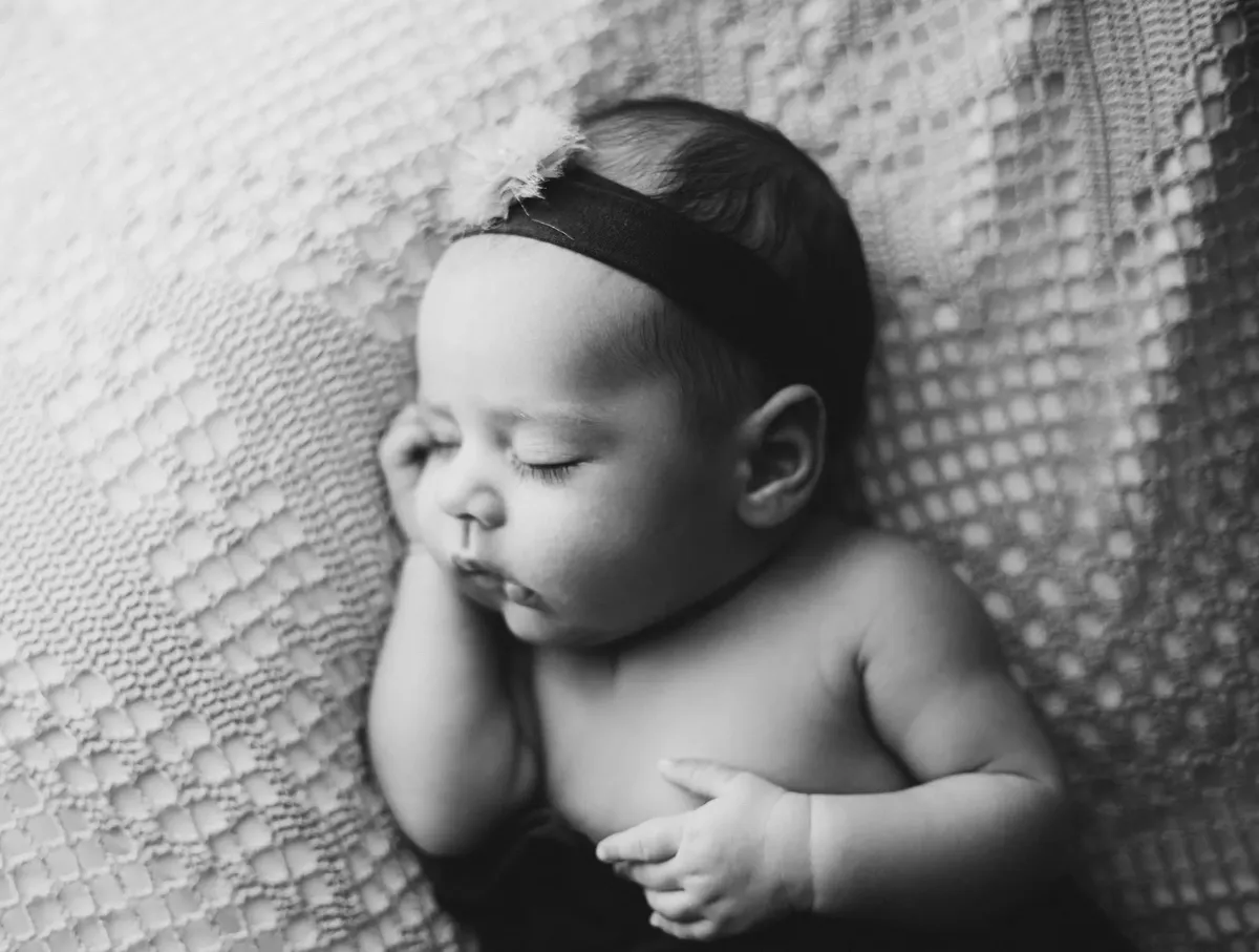 Neonata che dorme con fascia floreale su coperta a nido d'ape, bianco e nero