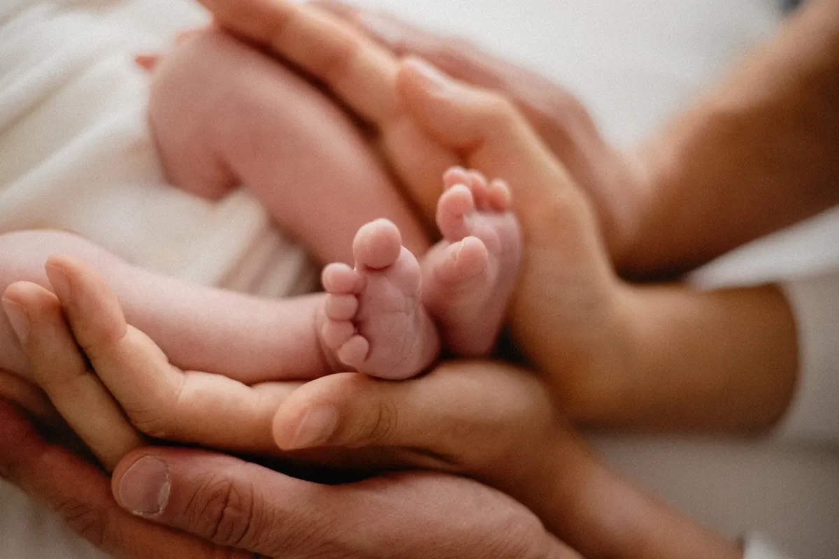 Piedini del neonato nelle mani dei genitori, dettaglio servizio fotografico newborn