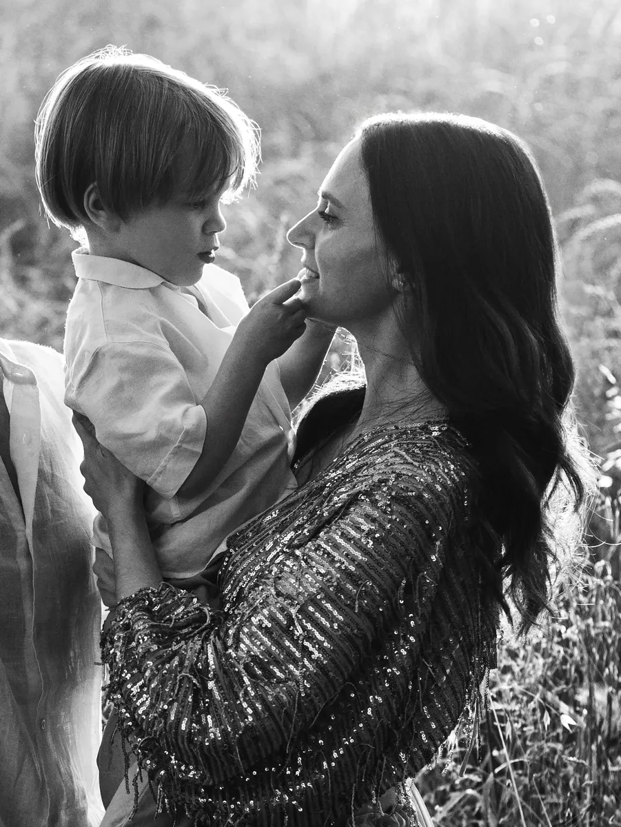 Mamma che tiene in braccio il figlio piccolo in un campo, sguardo complice in bianco e nero